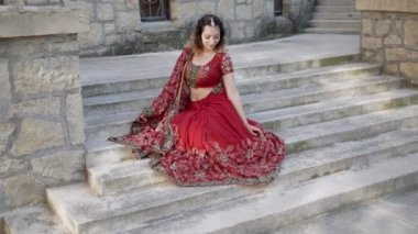 Şehrin antik mimari caddelerinde poz veren genç, güzel bir Hintli kadın. Kırmızı Sari giyinmiş, geleneksel süslemeler ve Mehendi desenleriyle süslenmiş.