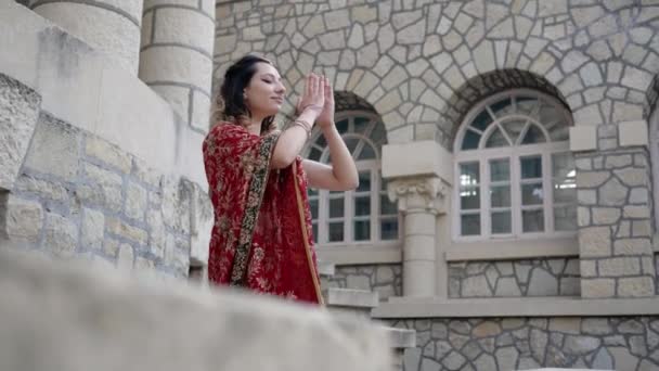 Une jeune femme dans un sari indien coloré se joint à Namaste, salutation traditionnelle hindoue. Belle femme souriante, exprime son respect et son hospitalité — Video