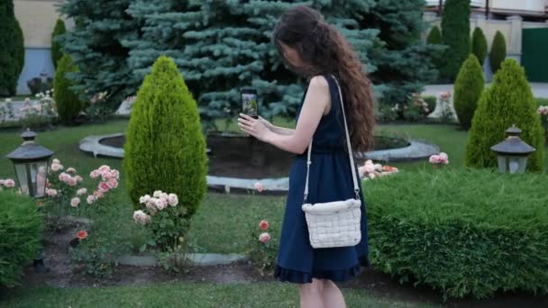 Giovane donna in giardino scattare foto al telefono graziosi fiori o piante rare — Video Stock