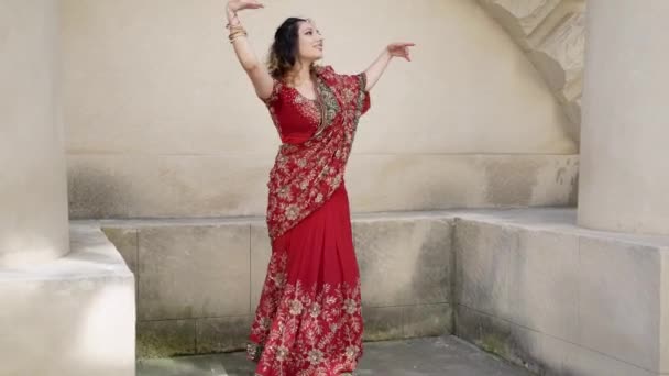 Jong mooi indiaans vrouw dansen in rood sari op achtergrond muren oud gebouw buiten — Stockvideo