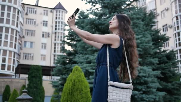 Jovem mulher em vestido bonito faz selfie no verão telefone na cidade — Vídeo de Stock