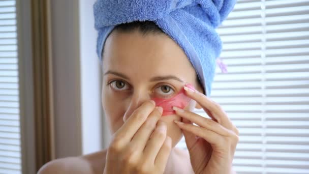 Joven hermosa mujer pasta parches bajo los ojos para el cuidado de la piel después de una ducha — Vídeo de stock