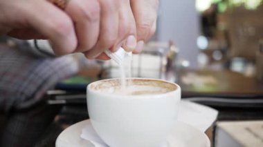 Adam bir poşet şekeri yakın plan kahve bardağına doldurur.