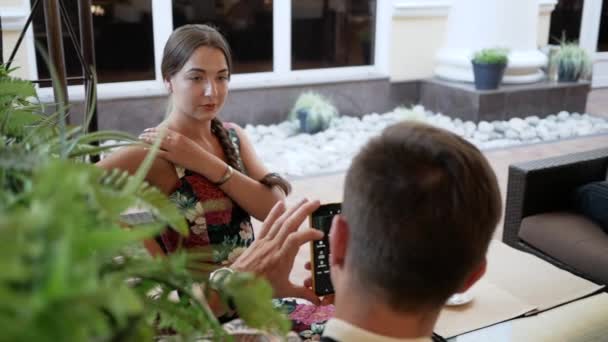 Joven fotografiado en el teléfono joven mujer. Esposo tomando fotos en el teléfono esposa — Vídeo de stock