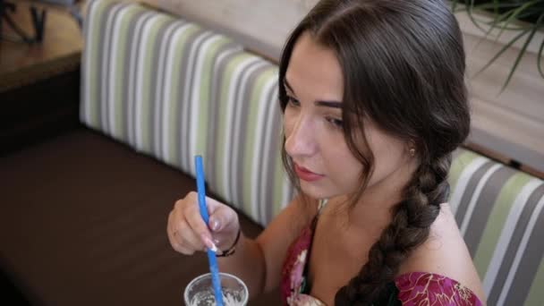 Schöne junge Frau in Restaurant rührt in Vorfreude Cocktailstroh — Stockvideo