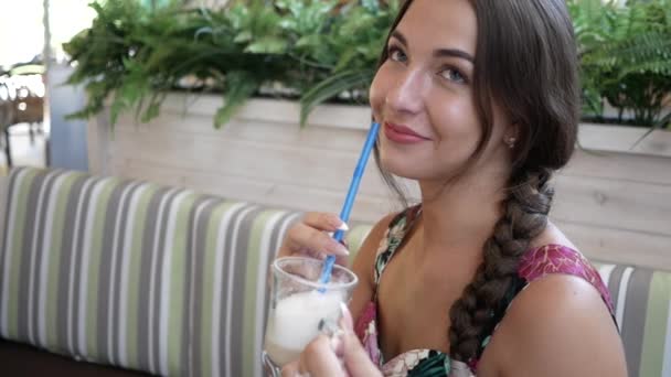 Mladá krásná žena v kavárně v létě nápoje koktejl přes trubice a úsměvy — Stock video