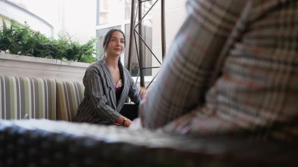 Jonge vrouw in een cafe is praten met de man en denken over iets — Stockvideo