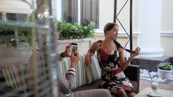 Jonge man neemt foto 's zijn vriendin in de zomer cafe met telefoon camera buiten — Stockvideo