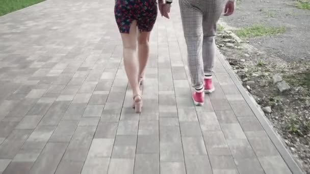 Vista de perto a partir de pés jovens mulheres e homens caminhando ao longo do caminho de azulejos — Vídeo de Stock