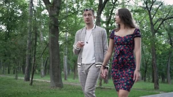Молодой человек и симпатичная женщина в платье гуляют на природе и разговаривают — стоковое видео