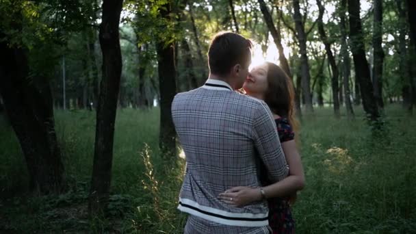 Feliz joven familia abrazo pareja en el parque de verano. resplandor del sol brilla en la cámara — Vídeos de Stock