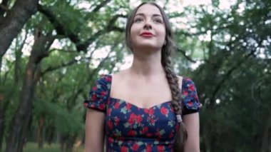 Şehir parkında örgü ve elbisesi olan güzel, gülümseyen bir kadın portresi