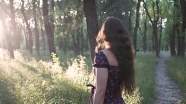 Kadın gün batımında ya da gün doğumunda Park 'ta uzun saçlarıyla başını sağa sola sallar.