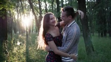 Sevimli, duygusal, genç, evli çift gün batımında Park 'ta gülüp sarılıp öpüşüyor.