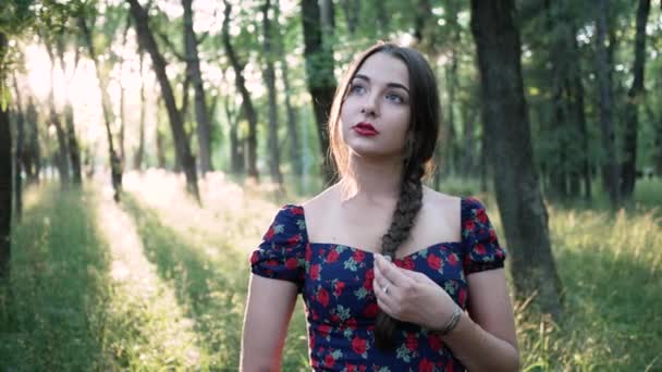 Портрет вдумчивой молодой красивой женщины в парке. яркие лучи солнца — стоковое видео
