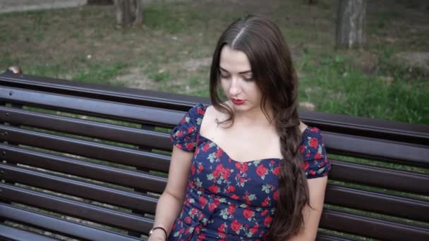 Jeune femme en été Park est assis sur le banc et le livre de lecture, tourne des pages — Video