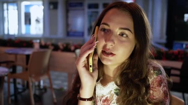 Porträtt kvinna talar på mobilen. Närbild ansikte ung flicka på café på kvällen — Stockvideo