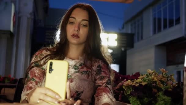 Wanita muda yang cantik menggunakan telepon sambil menunggu pesanan di kafe — Stok Video