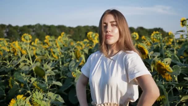 Молода красива жінка агроном, що стоїть на тлі поля з соняшниками — стокове відео