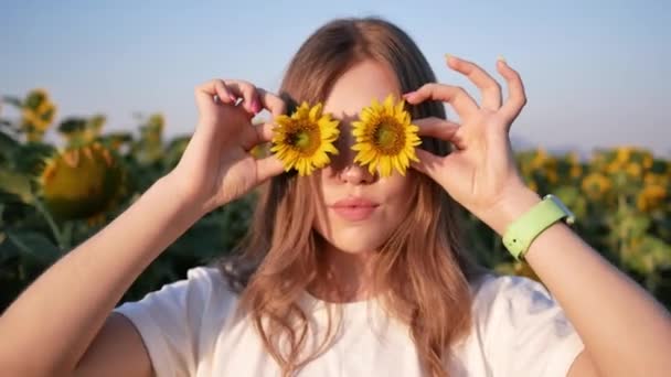 Joven hermosa mujer divertida posando con flores de girasol en caliente día de verano — Vídeos de Stock