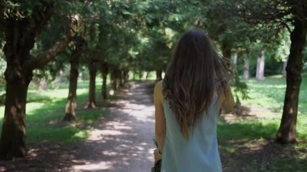 Godendo donna con mazzo di fiori percorso a piedi nel parco — Video Stock