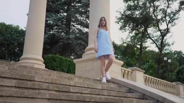 Joven bonita mujer en vestido azul está caminando por la gran escalera de la ciudad hermosa — Vídeo de stock