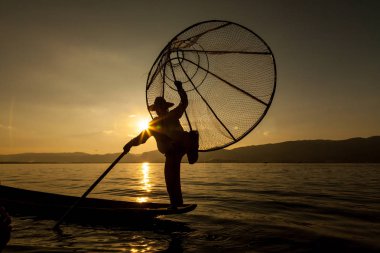 Inle Gölü, Myanmar - Kasım 2013 yaklaşık: Birmanya adam küçük bir tekne Inle gölde kürek. Inle yerliler kendi benzersiz bacak tekniği kürek için ünlü.