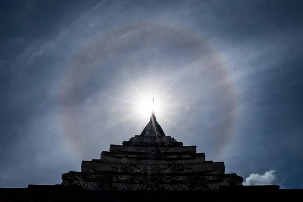 Sun halo over Thai temple roof, Thailand.