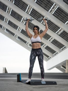 Açık havada eğitim ve karın egzersizleri ve dumbbells bir sokakta Barselona fitness kadın