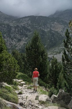 Yürüyüş bir hasır şapka ve sırt çantası ile kadın İspanyolca Pyrenees aracılığıyla