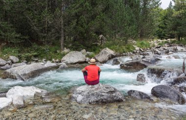 Yürüyüş bir hasır şapka ve sırt çantası ile kadın İspanyolca Pyrenees aracılığıyla