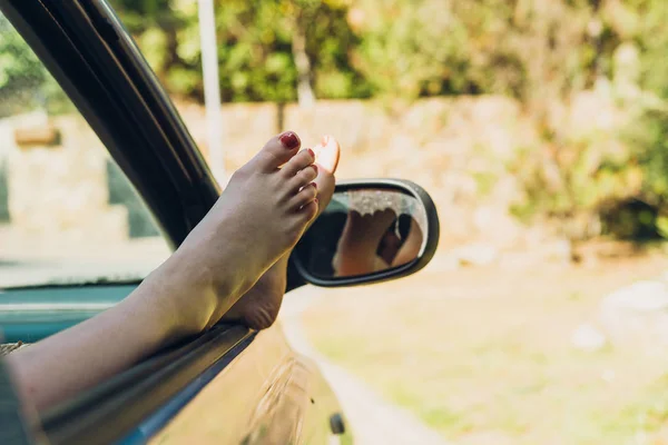 Mädchen mit den Füßen aus dem Autofenster beim Sonnenbaden auf einem — Stockfoto