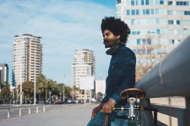 Afro saçlı adam bir vintage tarzı bisiklet sürme 