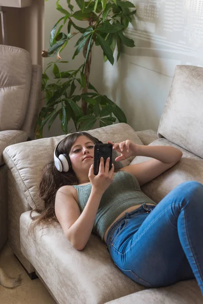 Tiener meisje liggend op de Bank van haar huis kijken naar haar telefoon — Stockfoto