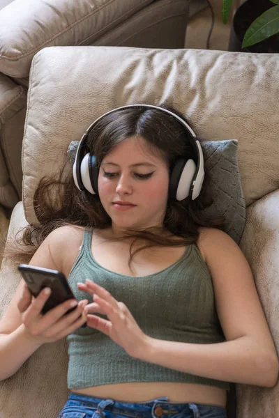 Teenagermädchen liegt auf der Couch ihres Hauses und schaut auf ihr Handy — Stockfoto