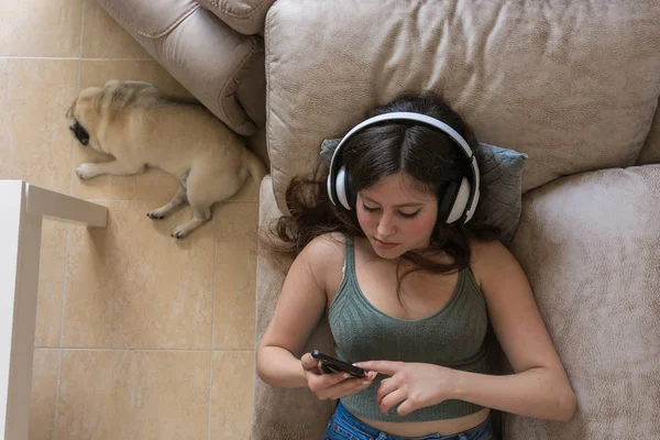 Teenagermädchen liegt auf der Couch ihres Hauses und schaut auf ihr Handy — Stockfoto
