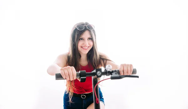 Chica conduciendo un scooter eléctrico con una cara de velocidad . — Foto de Stock