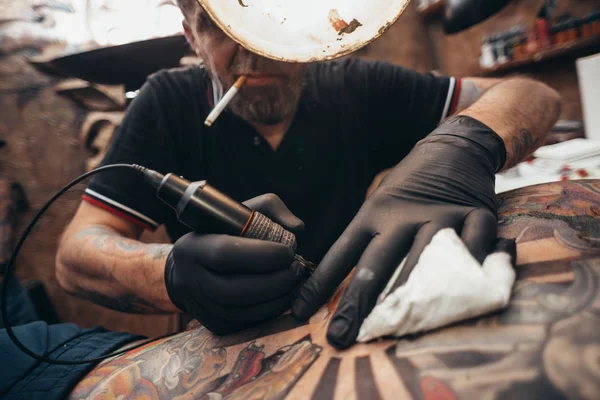 Close up of the tattoo machine. Tattooing. Man creating a picture on his back by a professional tattoo artist.