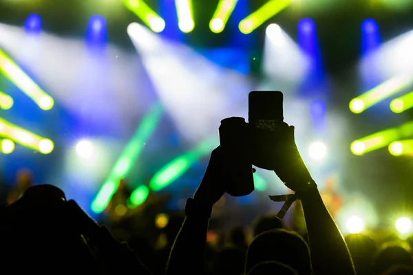 People taking photographs with smart phone during a concert