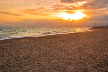 Sarı Güneş bulutların arasından Denizi üzerinden geliyor ile güzel bir plaj gün batımı