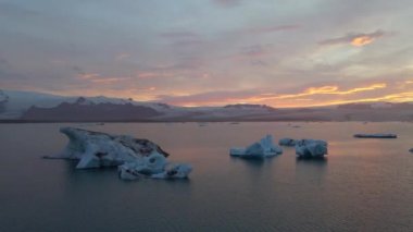 İzlanda 'daki Glacier Lagoon Jokulsarlon' un renkli günbatımı ışıklarında çekilmiş yüksek kaliteli 4K görüntüleri. Buzdağlarıyla dolu göl İzlanda 'da ziyaret edilecek en manzaralı yerlerden biridir.