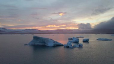 İzlanda 'daki Glacier Lagoon Jokulsarlon' un renkli günbatımı ışıklarında çekilmiş yüksek kaliteli 4K görüntüleri. Buzdağlarıyla dolu göl İzlanda 'da ziyaret edilecek en manzaralı yerlerden biridir.