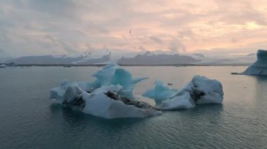 İzlanda 'daki Glacier Lagoon Jokulsarlon' un renkli günbatımı ışıklarında çekilmiş yüksek kaliteli 4K görüntüleri. Buzdağlarıyla dolu göl İzlanda 'da ziyaret edilecek en manzaralı yerlerden biridir.