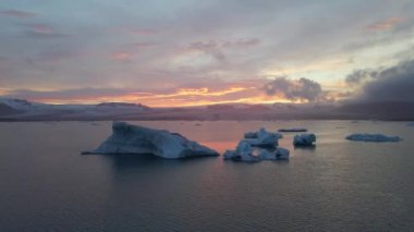 İzlanda 'daki Glacier Lagoon Jokulsarlon' un renkli günbatımı ışıklarında çekilmiş yüksek kaliteli 4K görüntüleri. Buzdağlarıyla dolu göl İzlanda 'da ziyaret edilecek en manzaralı yerlerden biridir.