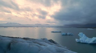 İzlanda 'daki Glacier Lagoon Jokulsarlon' un renkli günbatımı ışıklarında çekilmiş yüksek kaliteli 4K görüntüleri. Buzdağlarıyla dolu göl İzlanda 'da ziyaret edilecek en manzaralı yerlerden biridir.