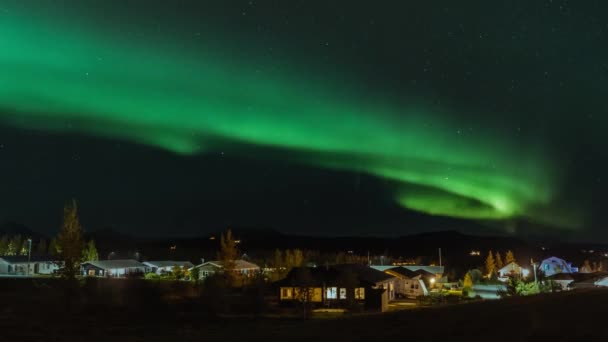 A táncoló aurora borealis ideje lejárt az éjszakai égbolton. Gyönyörű északi fények Izlandon a kis falu felett. Egy kiváló minőségű 4K videó — Stock videók