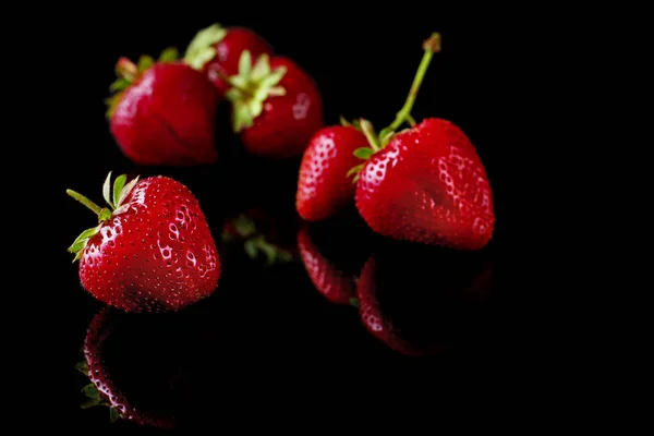 Morangos vermelhos maduros em um fundo preto — Fotografia de Stock