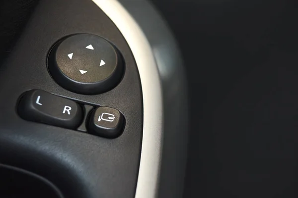 Car door lock, window button and side mirror adjuster button on a car.