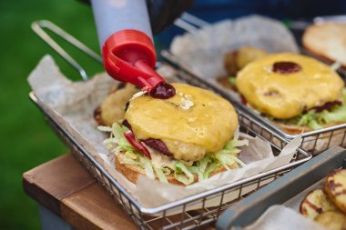 Açık havada büyük bir hamburger yemek yakın, Şef ketçap, patates ile ekler. Fast food, yemek, seçici odak