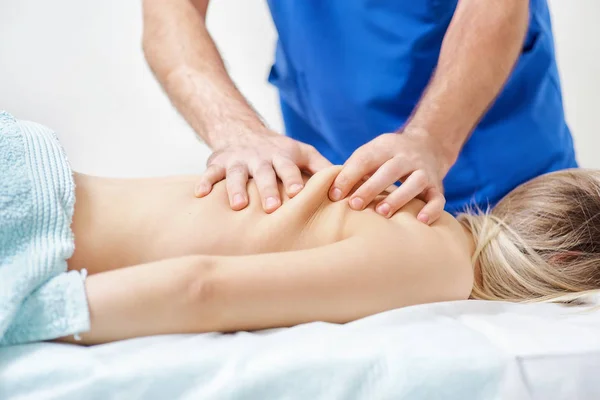 Physiotherapist doing healing treatment on man\'s back. Therapist wearing blue uniform. Osteopathy. Chiropractic adjustment, patient lying on massage table. Prevention of back treatment close-up.